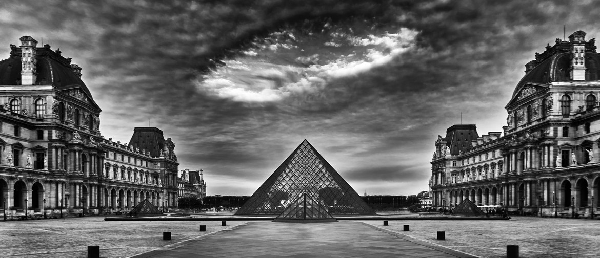 A photograph of the Louvre Museum in Paris, with a distinctive cloud formation over top of the glass pyramid. There are no tourists or people in the photo.