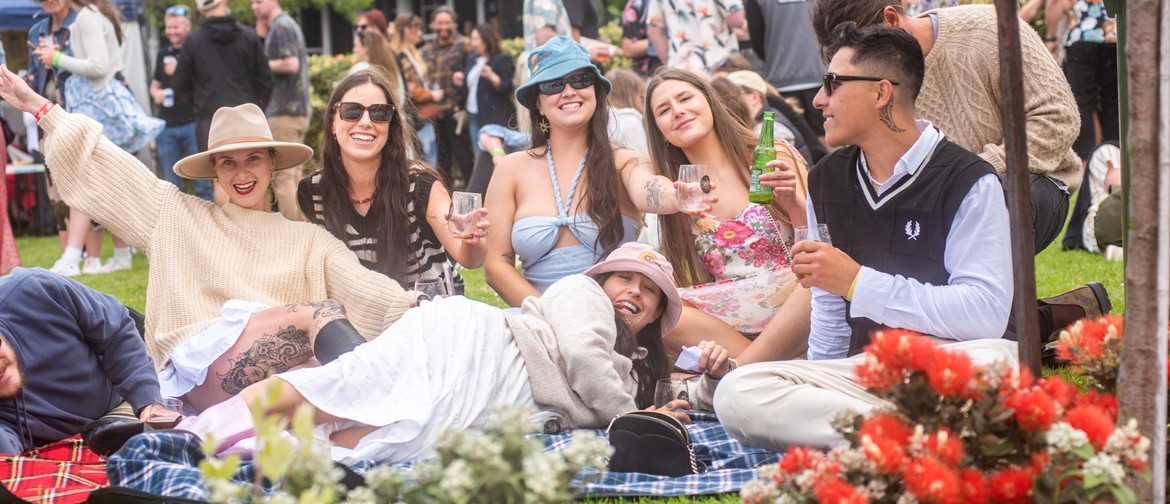 Group of friends sitting on picnic rug at wine festival
