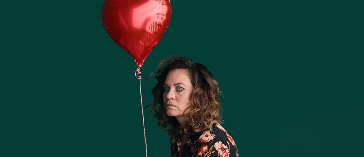 A woman who looks comically disturbed, sits staring out into the distance. She is wearing a floral shirt and a red heart-shaped balloon attached to a string floats above her head.