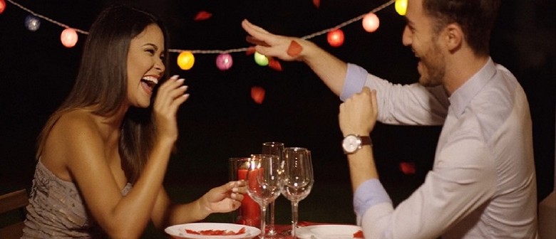 Speed Dating 30-44, 45-59 A woman and a man sit opposite each other across a small table. They have a glass of wine each. He has his arm raised and she is laughing